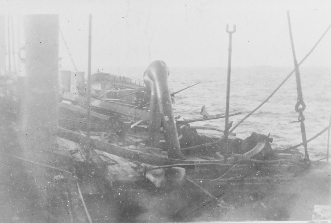 View from on board Santee taken after she was torpedoed on 27 December 1917, showing damage over her engine room hatch and the boat destroyed by the explosion. HMS Bluebell is faintly visible in the right distance. (Courtesy of Capt. David C. Han...