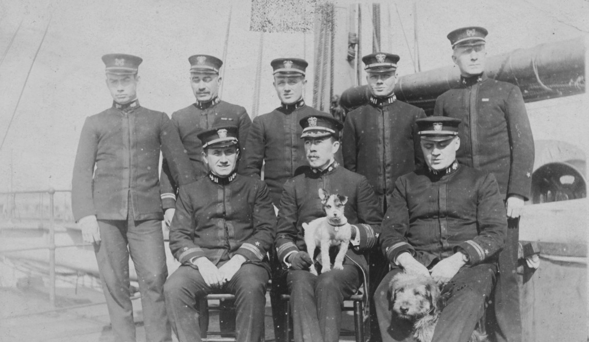 Ship’s officers in uniform on board Santee at Devonport, England, dry dock on 20 February 1918. Seated in front are (left to right): Lt. John R. Peterson, Jr.; Cmdr. David C. Hanrahan, Commanding Officer; and Lt. Robert E.P. Elmer. Standing are (...