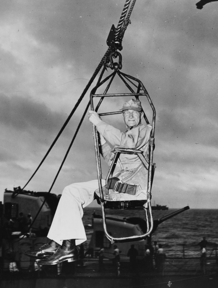 Vice Adm. Mitscher high-lines from a destroyer to Randolph (CV-15) via boatswain’s chair, 15 May 1945. This marks the third time in four days in which Mitscher transfers his flag, after kamikazes maul his two previous flagships, Bunker Hill and E...