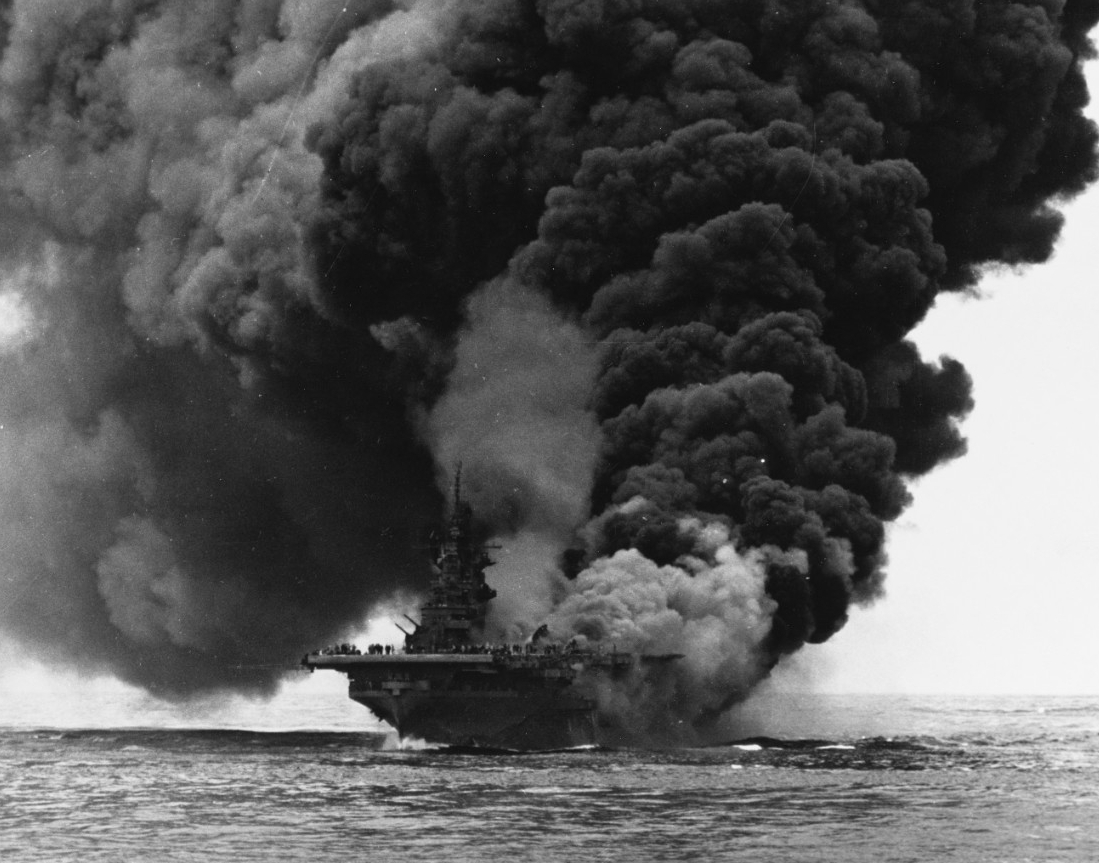 Burning and with heavy smoke pouring from the aft end of her flight deck as well as the hangar deck, Bunker Hill fights for her life some 60 miles off the shore of Okinawa after two kamikazes plunged into her, 11 May 1945. This photo is taken from Bataan (CVL-29). (U.S. Navy Photograph 80-G-274266, National Archives and Records Administration, Still Pictures Division, College Park, Md.)