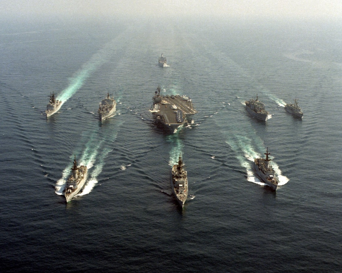 Kitty Hawk Battle Group underway in the Pacific Ocean, 1987. Front row, left to right: frigate Stein (FF-1065), guided missile cruiser Halsey (CG-23), frigate Barbey (FF-1088); second row: Callaghan, ammunition ship Mount Hood (AE-29), aircraft carrier Kitty Hawk (CV-63), combat stores ship Mars (AFS-1), guided missile frigate Vandegrift (FFG-48). The fleet oiler Willamette (AO-180) follows. (U.S. Navy Photograph DN-SC-87-10327, PH2 Hensley, National Archives and Records Administration, Still Pictures Division, College Park, Md.)
