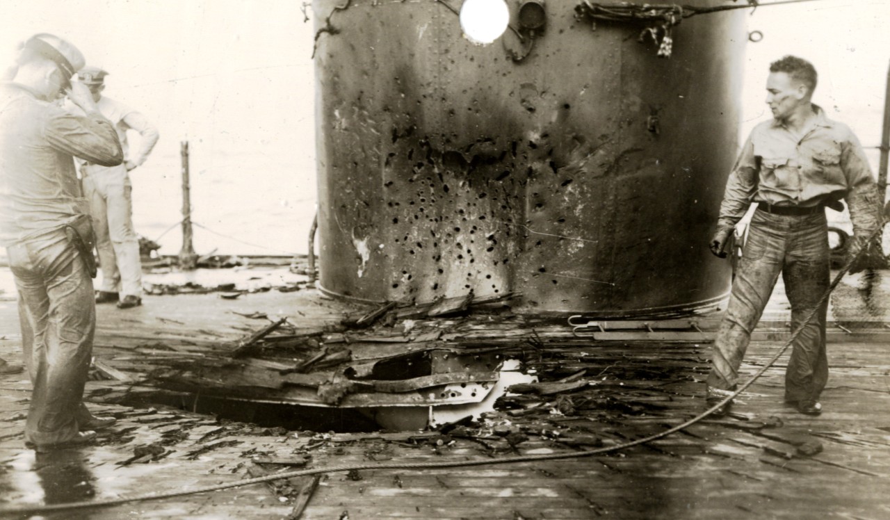 Officers and enlisted men on board Chester, 1 February 1942, view the damage from the bomb that hit her well deck.