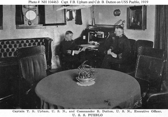Halftone reproduction of a photograph, taken circa 1919, of Capt. Upham (left) at his desk, with Cmdr. Benjamin Dutton, the executive officer, at right. One of the ten images from the Souvenir Folder. (Donation of Dr. Mark Kulikowski, 2007, U.S. Navy Photograph NH 104463, Photographic Section, Naval History and Heritage Command)