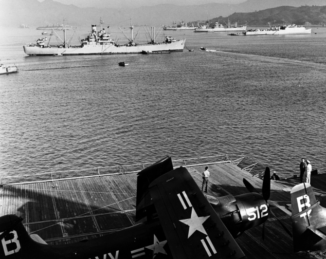 U.S. Navy ships take on supplies while moored in Sasebo harbor, circa December 1950. The photograph was taken from Princeton (CV-37). Among the ships in the background are Mount Katmai (AE-16), in left center, and Comstock, at right. Aircraft on Princeton's deck are Douglas AD-4 Skyraiders. (U.S. Navy Photograph, National Archives Still Pictures Branch, 80-G-423620).