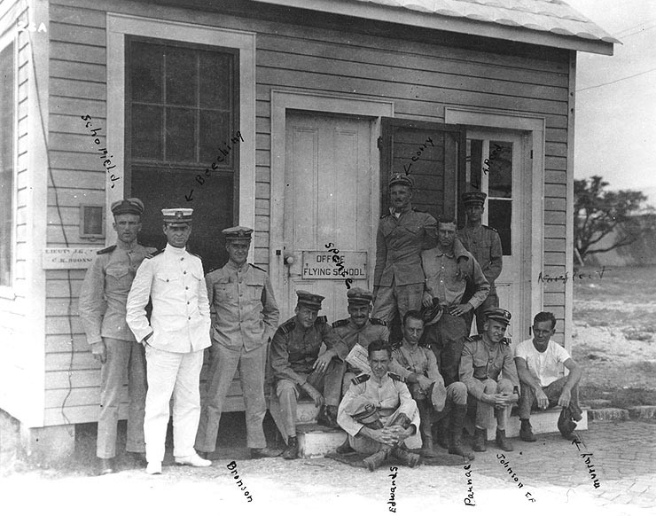 Some of the earliest U.S. Naval Aviators gather at the Flying School office, named for Lt. (j.g.) Clarence K. Bronson, at Naval Aeronautical Station Pensacola, circa 1915. Standing from left–right: Ens. Harold W. Scofield, Passed Assistant Surgeon Charles L. Beeching, Lt. (j.g.) Bronson, Lt. (j.g.) Corry, Lt. (j.g.) Joseph P. Norfleet, and Lt. Albert C. Reed. Seated left–right: an unidentified Lt. (j.g.), Lt. (j.g.) Earl W. Spencer Jr., Lt. (j.g.) Walter A. Edwards, Lt. (j.g.) Robert R. Paunack, Lt. Earle F. Johnson, and Lt. (j.g.) George D. Murray. (Naval History and Heritage Command Photograph NH 90232)