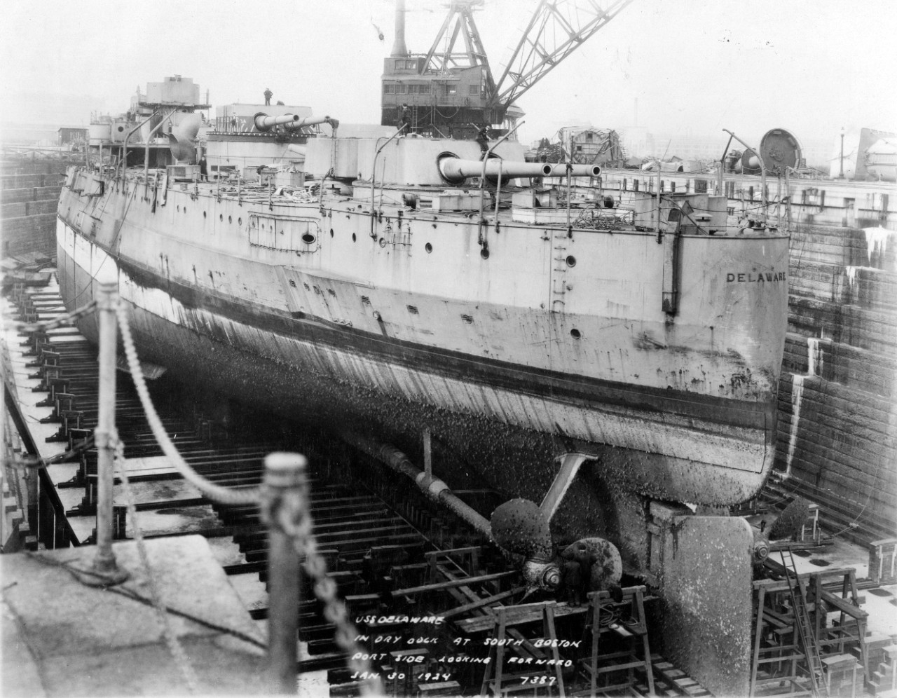 Delaware in dry dock at the South Boston Annex, Boston Navy Yard, Mass., on 30 January 1924. The ship has been stripped in preparation for scrapping. Note propellers, rudder, armor belt and heavy fouling on her underwater hull. (Naval History and Heritage Command Photograph NH 54675)