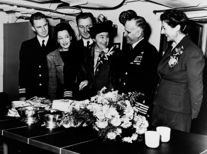 Mrs. Helen K. Boone (center), the ship’s sponsor, cut the cake during the commissioning ceremony at Seattle, Wash., 26 December 1944. Cmdr. Ray M. Pitts, the ship’s first commanding officer, stands to her right. (Unattributed U.S. Navy Photograph NH 67423, Photographic Section, Naval History and Heritage Command)