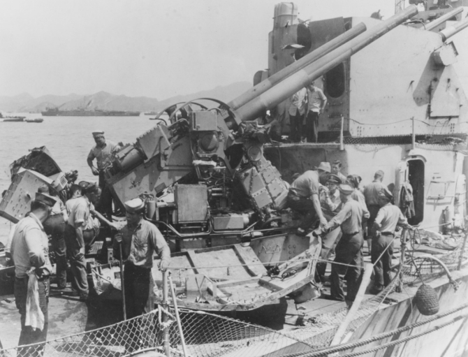 Sailors examine the damage to the forward 5-inch gun following the Japanese kamikaze attack, most likely while anchored at Kerama Rettō. Note the cartoon on the rear of the gun. (Unattributed U.S. Navy Photograph 80-G-330102, Photographic Section, Naval History and Heritage Command)