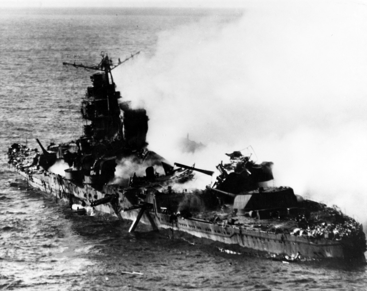 This close up picture shows the devastated ship in more detail. Her midships structure lies shattered, and both portside torpedo tubes are trained outboard. Parts of the aft superstructure, and possibly the mainmast, collapse across her No. 4 8-inch gun turret — the wreckage does not comprise Capt. Fleming’s Vindicator, which crashes into the sea. (U.S. Navy Photograph 80-G-414422, National Archives and Records Administration, Still Pictures Section, College Park, Md.)