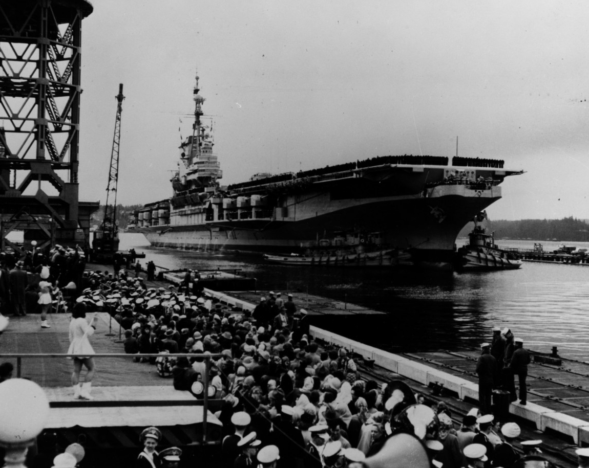 A crowd of well-wishers including a Navy band and drum majorettes greet Franklin D. Roosevelt as she arrives at Puget Sound Naval Shipyard for her conversation, 5 March 1954. (Naval History and Heritage Command Photograph NH 79667)