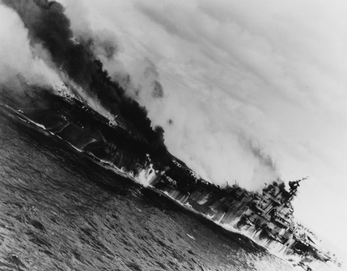 Franklin burning and down by the stern after being hit by two 550-pound Japanese semi-armor piercing bombs on 19 March 1945. (U.S. Navy Photograph 80-G-273867, National Archives and Records Administration, Still Pictures Division, College Park, Md.)