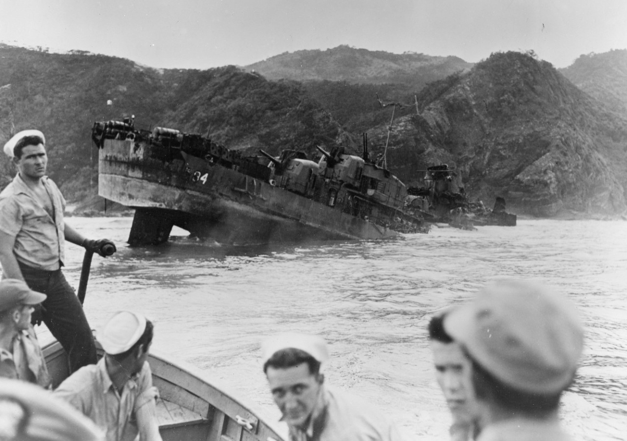 As the inspection party pulls away from Halligan’s torn and battered wreck (the hole at the fantail from a Japanese shore battery shell), their faces seem to reflect the devastation that they had just seen. (U.S. Navy Photograph 80-G-324187, Nati...