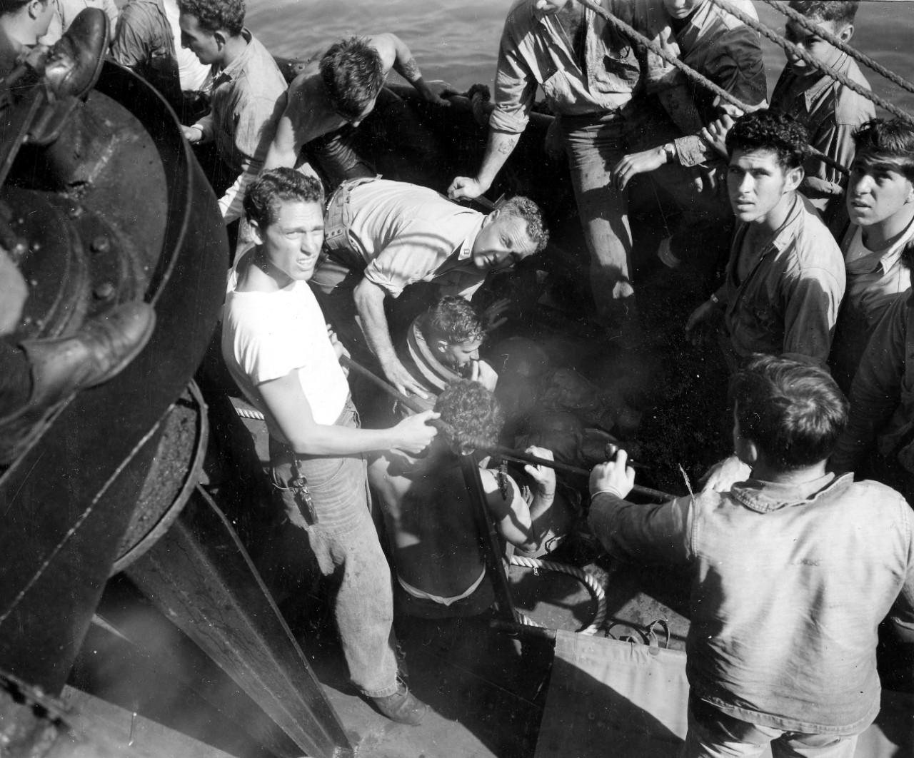 Lt. Robert S. Hurlbut, MC-V(G), USNR, Halligan’s medical officer, provides first aid for a pilot –evidence suggests perhaps Lt.(j.g.) Currier -- who has been rescued after a water landing (note aviator’s blown-up life vest collar). Hurlbut -- bor...
