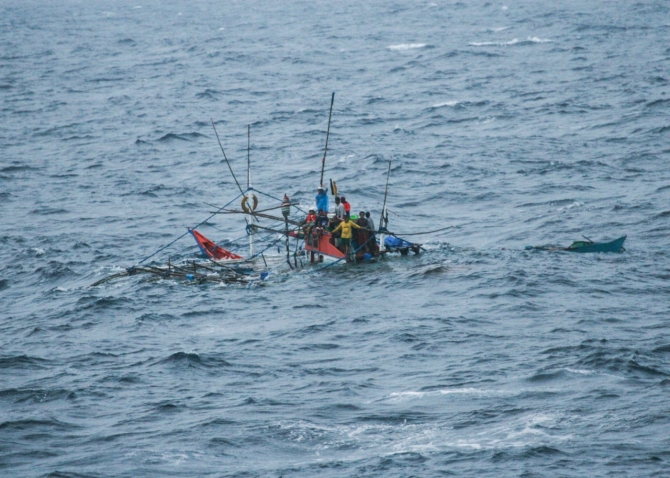 Terrified fishermen cling precariously to their sinking fishing boat in the South China Sea, 19 July 2015. (Unattributed U.S. Navy Photograph 150719-N-ZZ999-005, Navy NewsStand).