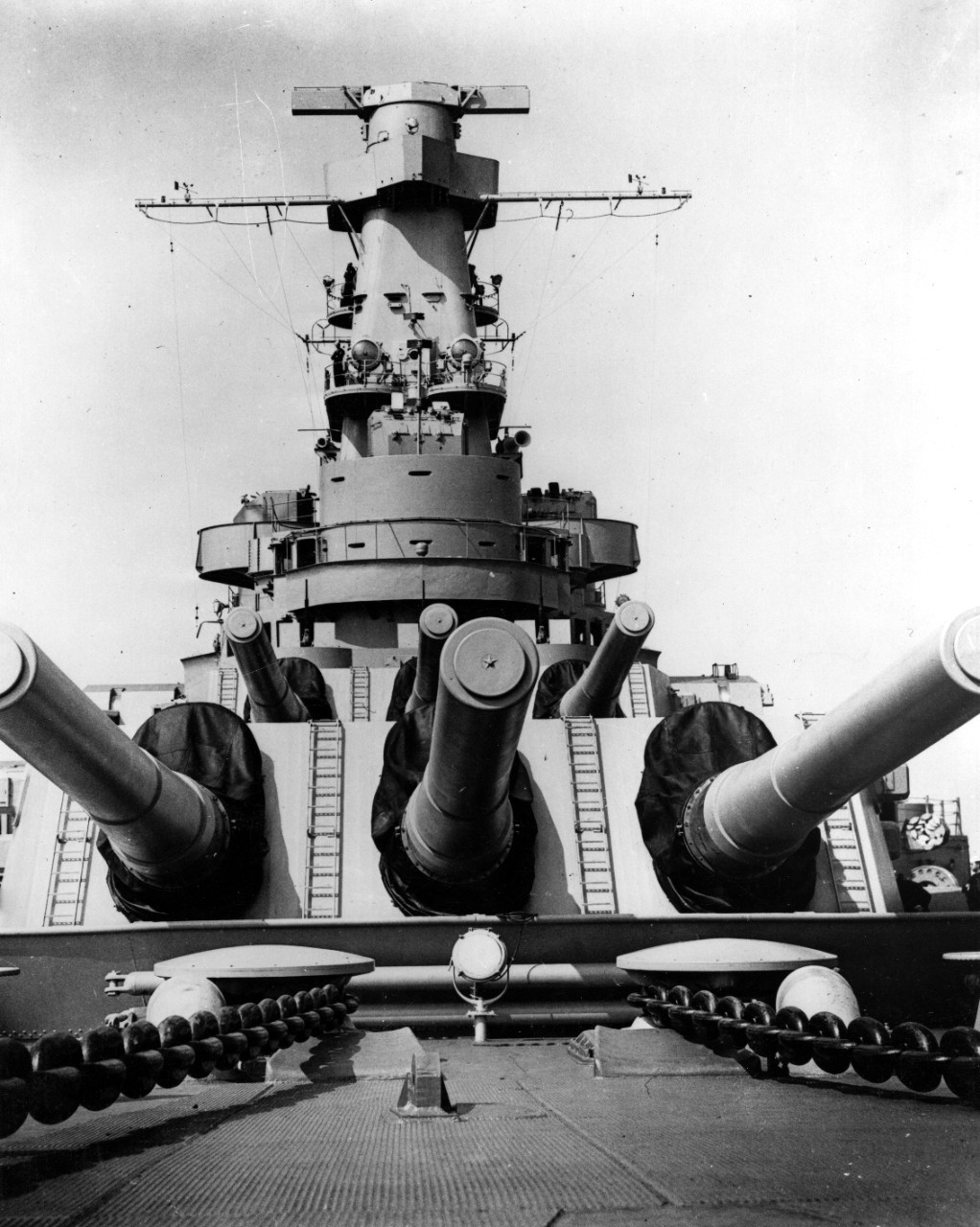 A view of Indiana and her forward 16-inch 45-caliber guns, taken at Newport News, Va., on the day of her commissioning, 30 April 1942. Note the anchor chains and capstains, armored conning tower and Mk 38 main battery director atop her superstructure. Fire control radar antennas have not yet been fitted atop her gun directors. (U.S. Navy Photograph 80-G-6692, National Archives and Records Administration, Still Pictures Division, College Park, Md.)