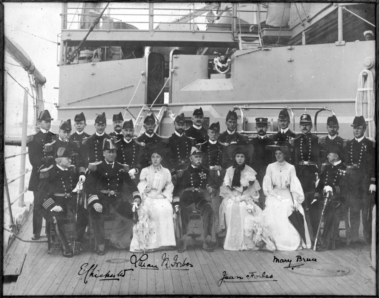 Officers, three ladies, and a British flag officer pose for the photographer on board Kearsarge at Portsmouth, England, 13 July 1903. Seated in the front row are (left to right): Capt. Joseph N. Hemphill, the ship’s commanding officer; Rear Adm. Sir Edward Chichester, RN; Lilian M. Forbes; Rear Adm. Charles S. Cotton; Jean Forbes; Mary Bruce; and an unidentified U.S. Navy commander. Identifiable among those standing are: Ens. Henry G.S. Wallace (behind Hemphill); and Lt. Charles L. Hussey, Cotton’s flag secretary (sporting a full beard, and behind the admiral). (Naval History and Heritage Command Photograph NH 105058)