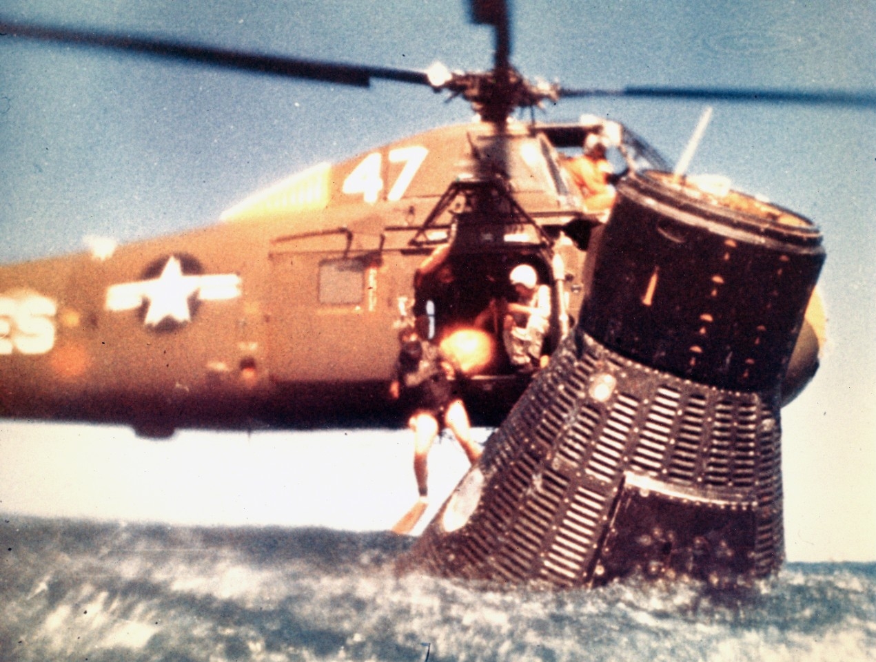 A Navy swimmer dives into the water from Seabat No 47 to work with Cooper within Faith 7 following his splashdown in the Pacific, 16 May 1963. (Naval History and Heritage Command Photograph UA 343.01.02)