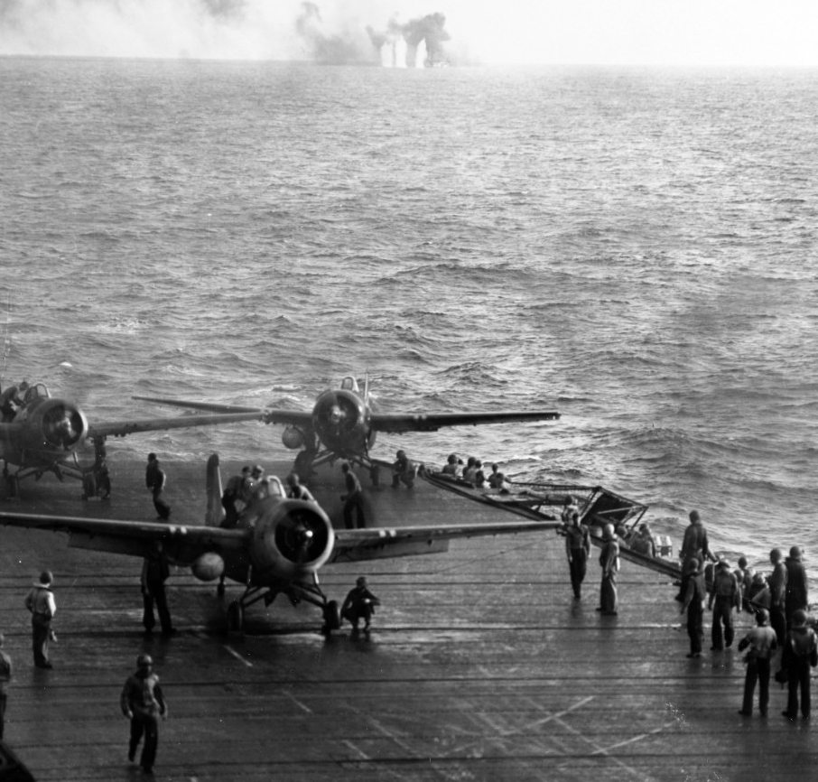 Men scramble to launch Wildcats as the enemy surprises Kitkun Bay off Samar, 25 October 1944. The fighter on the port quarter of the ship’s flight deck turns quickly to get into the action as the planes launch rapidly in the desperate circumstances. Japanese shells splash around White Plains in the center distance. (U.S. Navy Photograph 80-G-287497, National Archives and Records Administration, Still Pictures Division, College Park, Md.)