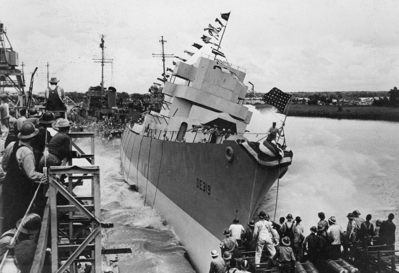 While those on board hang on for the ship’s entry into the water, Leopold slides down the ways as workmen, in the foreground and elsewhere in the vicinity, pause momentarily to see another one of the fruits of their labors begin her journey to take the war to the Axis. (U.S. Navy Photograph 80-G-74240, National Archives and Records Administration, Still Pictures Division, College Park, Md.)