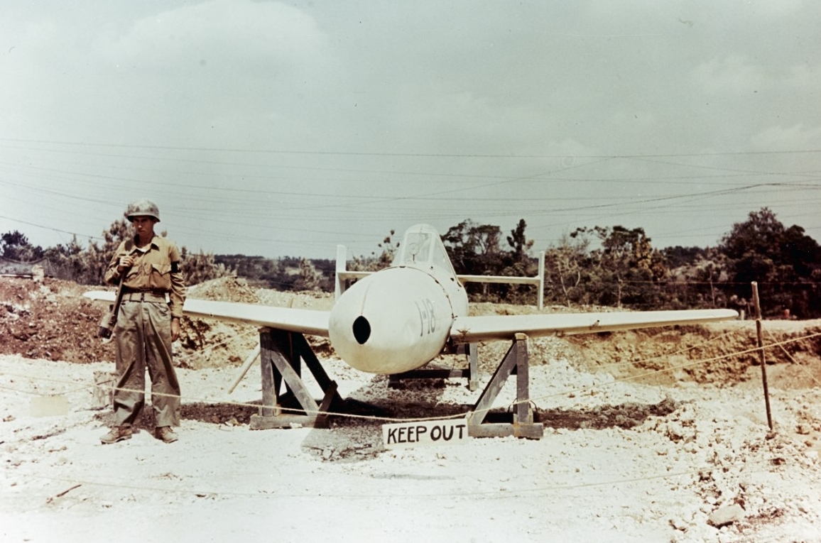 A captured Japanese Yokosuka MXY7 Ohka Model 11 suicide attack weapon guarded by an American MP at Yontan Airfield, Okinawa, circa April-May 1945. (U.S. Navy Photograph 80-G-K-4930, National Archives and Records Administration, Still Pictures Division, College Park, Md.).