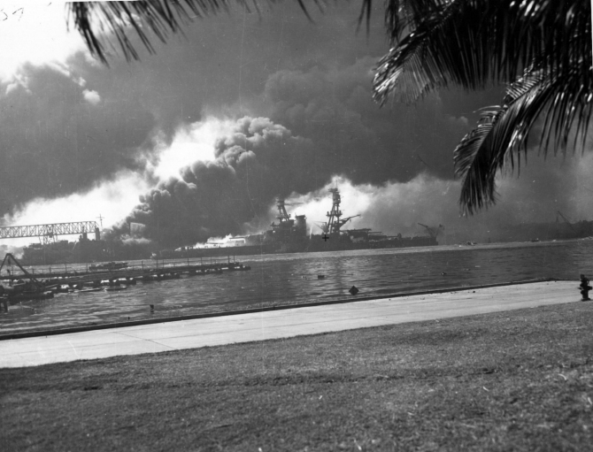 Nevada afire off the Ford Island seaplane base, with her bow pointed up-channel. Shaw (DD-373) burning in the floating dry dock YFD-2 is in the left background. Photographed from Ford Island, with a dredging line at left. (U.S. Navy Photograph 80-G-32457 National Archives and Records Administration, Still Pictures Division, College Park, Md.)