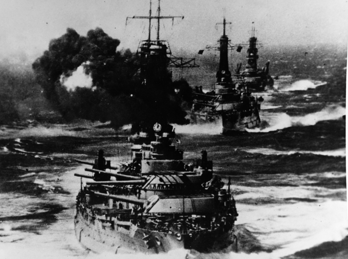 New York, in foreground, followed by Texas (BB-35), and Wyoming (BB-32), proceeding at full speed across the Pacific firing their guns during annual battle maneuvers. Courtesy of the San Francisco Maritime Museum, San Francisco, Calif., 1969. (Na...