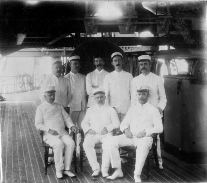 Staff and junior officers on board Olympia in Manila Bay, c. 1898. Those present include (seated left to right): Medical Inspector Abel F. Price; Pay Inspector Daniel A. Smith; and Capt. William P. Biddle, USMC; (standing left to right): Passed Assistant Surgeon John E. Page; unidentified; Assistant Engineer Edward H. De Lany (or Naval Constructor Washington L. Capps); Lt. Stokely Morgan; and Lt. (j.g.) Samuel M. Strite. (Unattributed or dated U.S. Navy Photograph NH 43348, Photographic Section, Naval History and Heritage Command)
