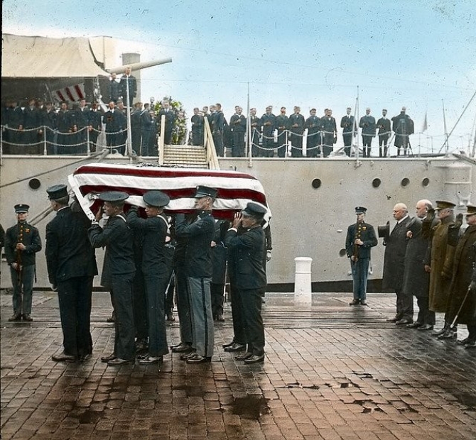 Casket bearers carry the Unknown Soldier from the ship and begin their procession to his eventual interment in Arlington National Cemetery, 9 November 1921. Some of the distinguished visitors standing to attention to the right include Secretary of War John W. Weeks; Secretary of the Navy Edwin Denby; Gen. of the Armies John J. Pershing, USA; Adm. Robert E. Coontz, CNO; and Maj. Gen. John A. Lejeune, USMC, Commandant of the Marine Corps. (Cruiser Olympia, Ships Collections, Independence Seaport Museum)
