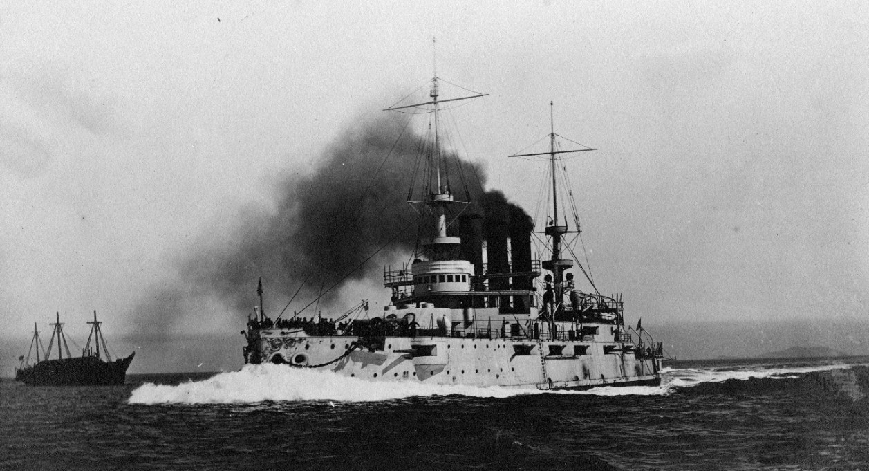 Ohio (Battleship No. 12) raises a proverbial bone in her teeth as she slices past Omaha (anchored in the left distance) while running her trials in San Francisco Bay, 26 July 1904. (Naval History and Heritage Command Photograph NH 63139)