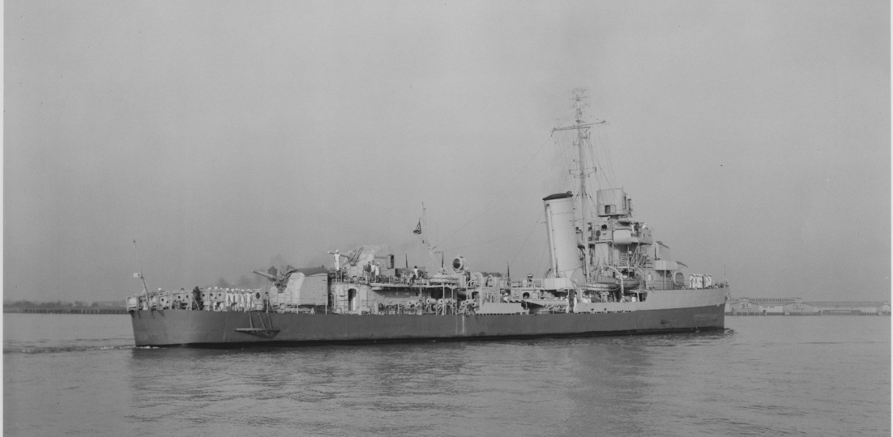 Rhind, her crew at quarters, 17 September 1942, near the Norfolk Navy Yard. Note the effectiveness of the graded camouflage. Also of interest is the white (with black shadowing) “E” markings on the gunhouses of Mt. 53 and 54. Other images in the series show an “E” on Mt. 51 as well. (U.S. Navy Bureau of Ships Photograph BS 34540, National Archives and Records Administration, Still Pictures Division, College Park, Md.)