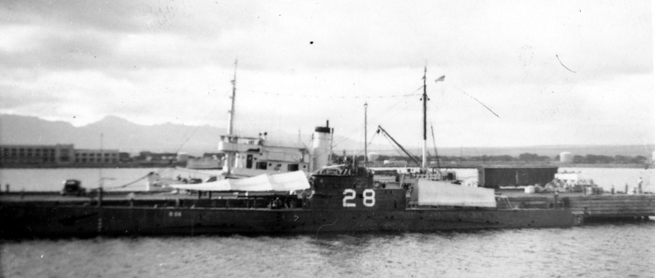 S-28, painted black with her identification number in white, alongside Ten-Ten Pier, Pearl Harbor, February 1939, with a fleet tug, probably Keosanqua, on the opposite side of the pier. (S-28 File, Ships History Collection, Naval History and Heritage Command)