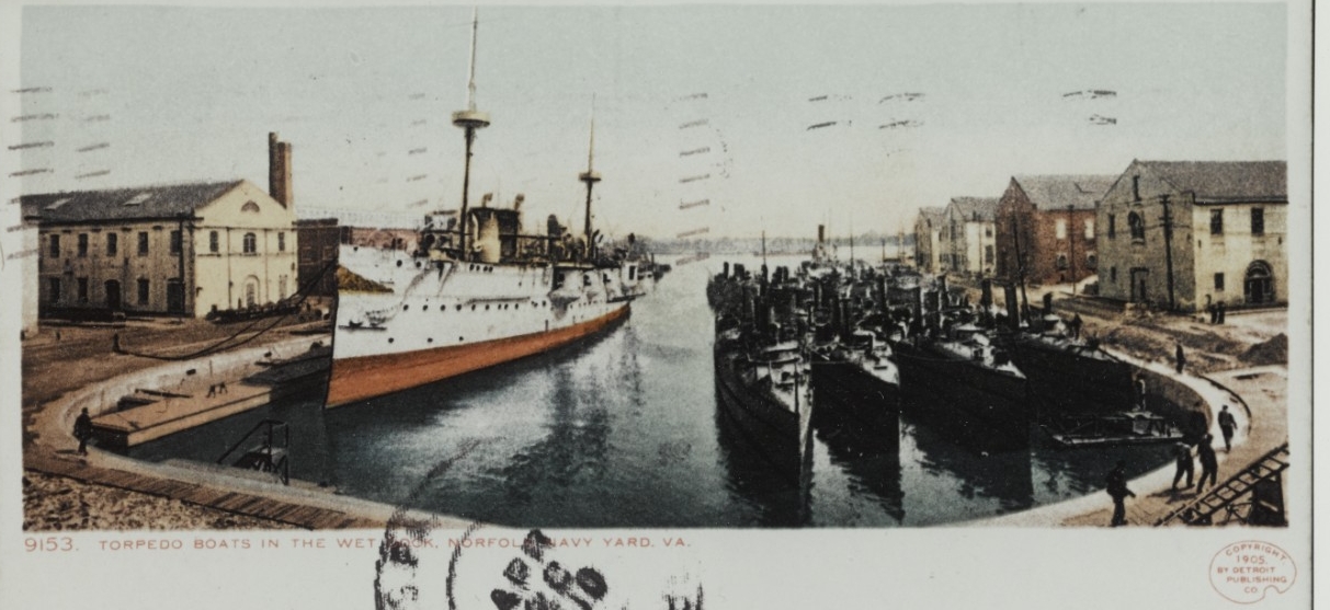 A cancelled postcard depicting the decommissioned San Francisco with torpedo boats in the Norfolk Navy Yard wet dock, 1905. (Naval History and Heritage Command Photograph NH 100043-KN)