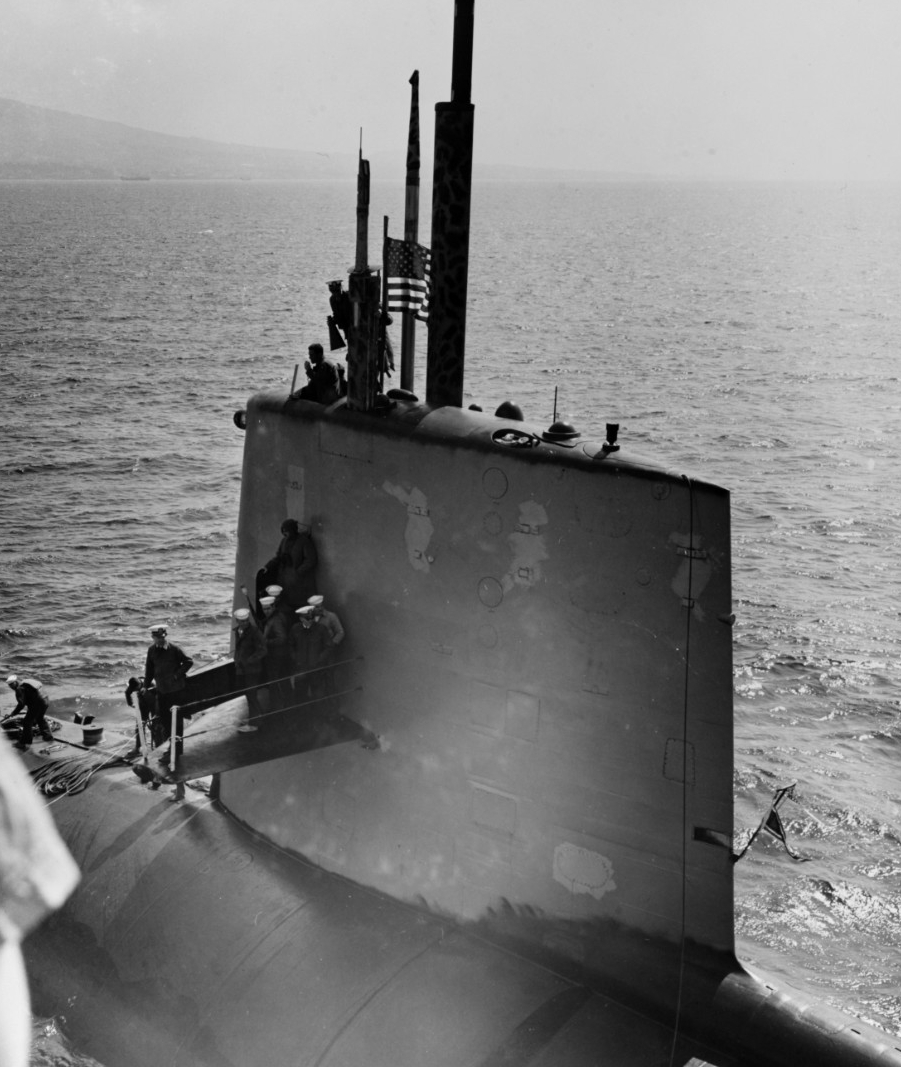 Scorpion pulls alongside advance aviation base ship Tallahatchie County (AVB-2) outside Naples, Italy, 10 April 1968. Cmdr. Francis A. Slattery, the submarine’s commanding officer, stands atop her sail, holding a megaphone. (Naval History and Heritage Command Photograph NH 70304)