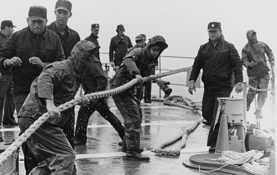 Rain from Hurricane Inez lashes sailors as they handle lines to get the ship underway for her shakedown cruise, 11 November 1975. (PH1 Lonnie M. McKay, Naval History and Heritage Command Photograph NH 96859)