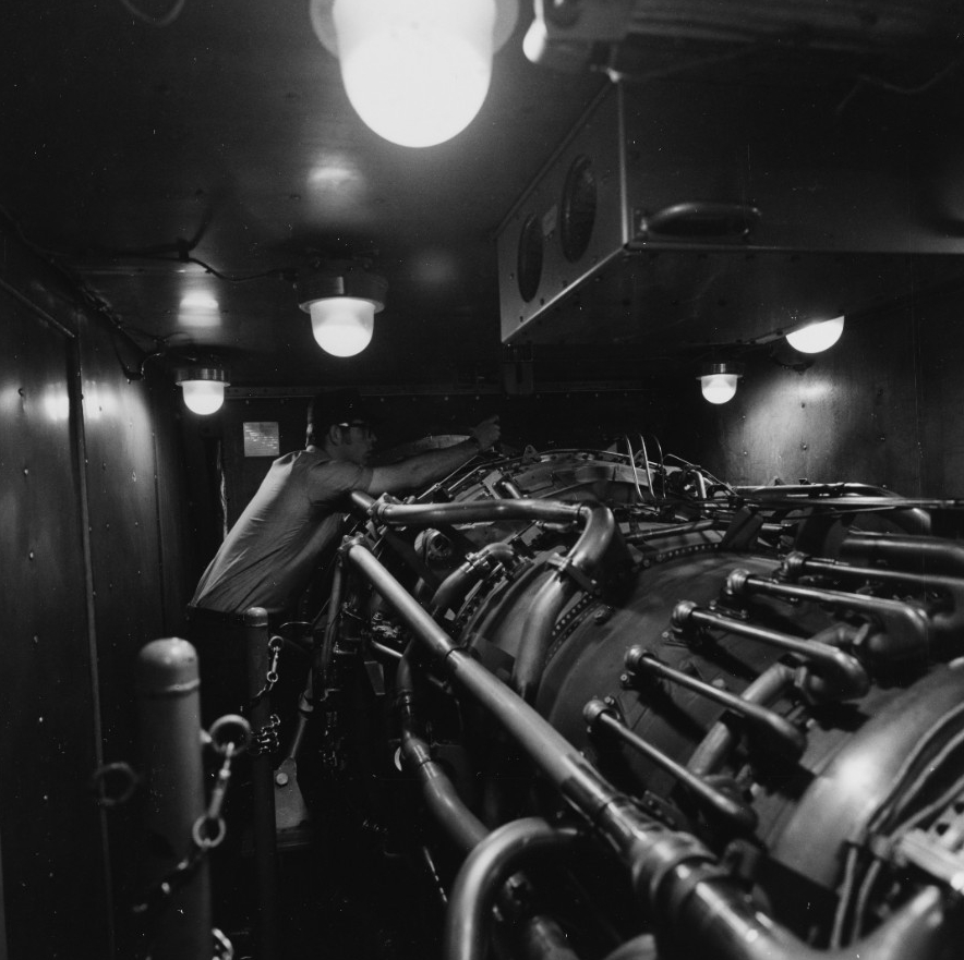 A crewman checks one of the ship’s four General Electric LM2500 marine gas turbine main engines during her trials, May 1975. (Naval History and Heritage Command Photograph NH 1162171)