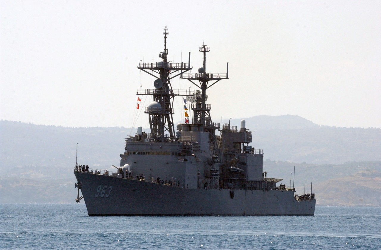 The dressed ship, her colorful flags flapping in the warm Mediterranean breeze, stands into Souda Bay for a visit, 19 July 2004. (Paul Farley, U.S. Navy Photograph 040719-N-0780F-047, Navy NewsStand)