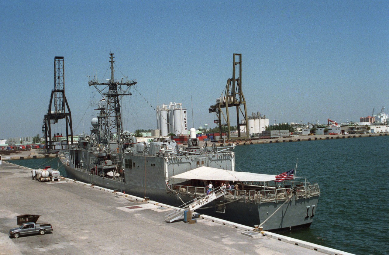 Stark takes a brief rest from her counter narcotics and humanitarian patrols and moors at Port Everglades, Fla., 23 May 1994. This port quarter view shows her with a relatively fresh coat of paint, and an awning stretched over the quarterdeck to protect watchstanders and visitors from the scorching tropical sun. (Operations Specialist 2nd Class John Bouvia, Department of Defense Photograph DN-SC-03-10051, Still Pictures Branch, National Archives and Records Administration II, College Park, Md., Photograph 6609123)