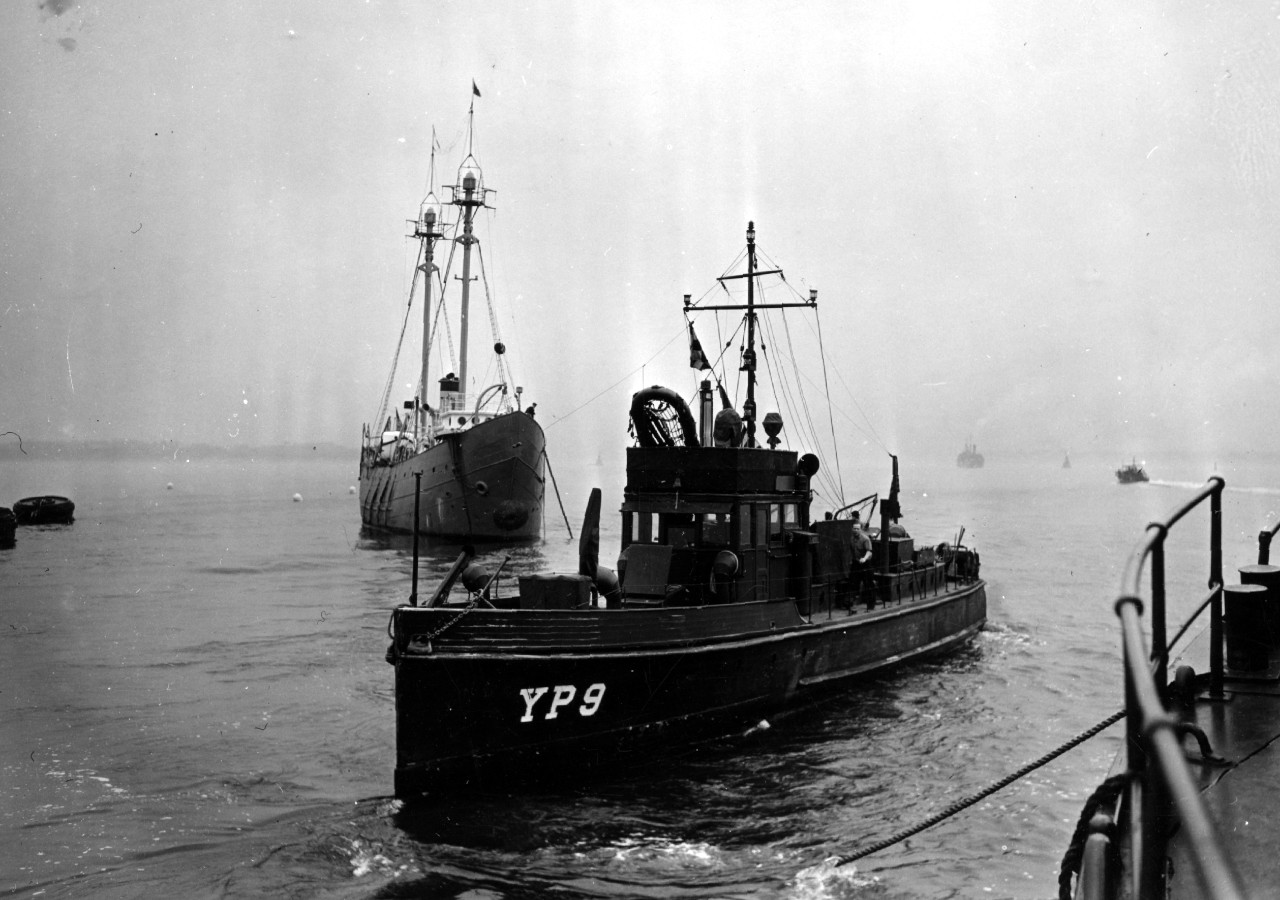 YP-9, her identification number rendered in a more standard format, comes alongside the gate vessel YNg-3, off Tompkinsville on 4 April 1942. Note lightship Ambrose in background and the life raft placed atop the chart house. (U.S. Navy Photograp...