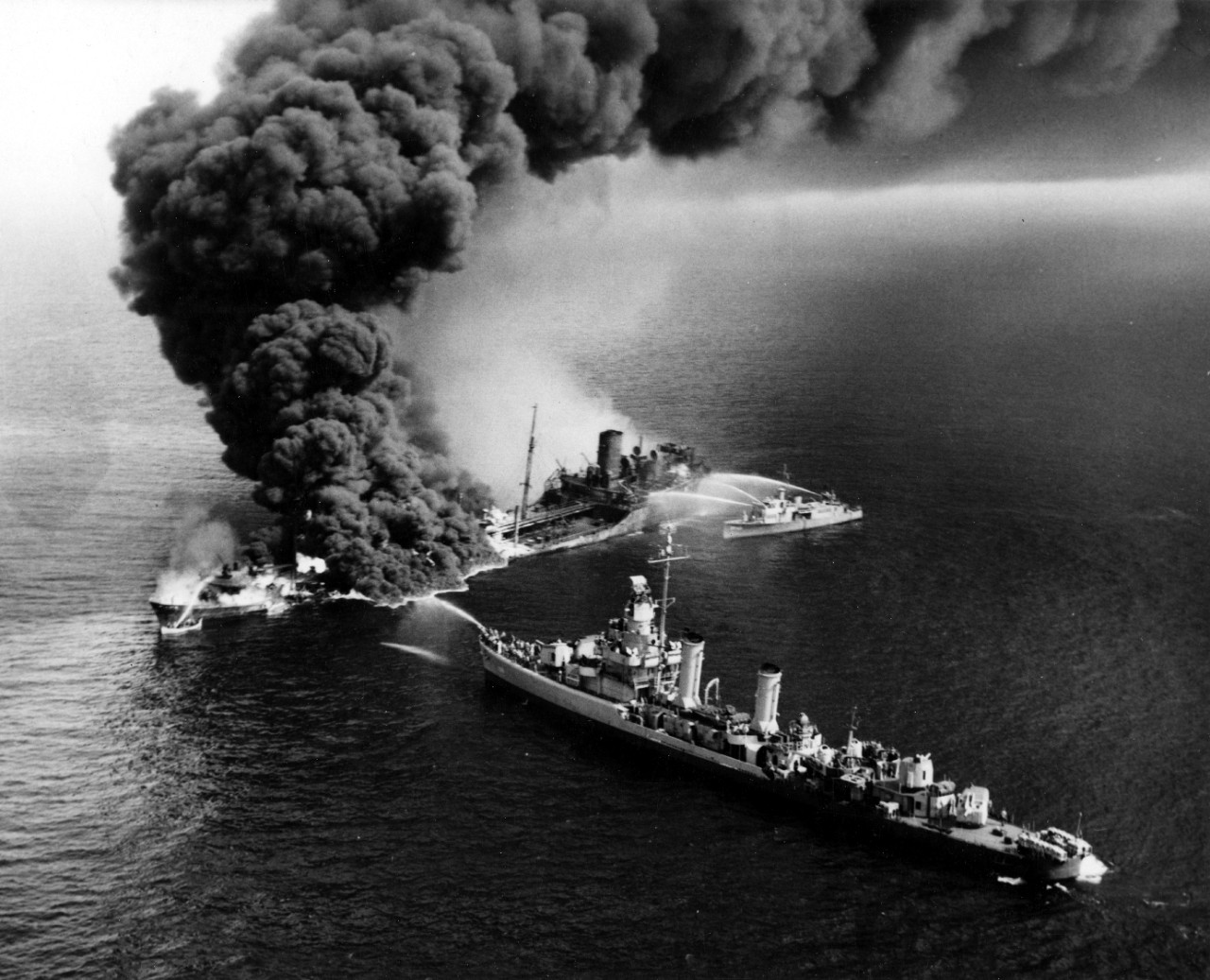Aided by a small boat (visible near the burning ship’s bow) and the destroyer Shubrick (DD-639), YP-261’s crew and her embarked firefighters direct three streams of water on the flames threatening to consume the tanker Montana, 1 June 1943. (U.S....