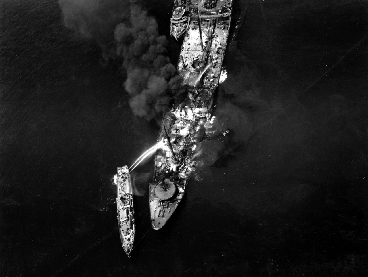 YP-261, a line to Montana’s bow, fights the last of the fires on board the burning tanker in a view probably taken on 2 June 1943, when the firefighters finally gained the upper hand. (U.S. Navy Photograph 80-G-68490, National Archives and Record...