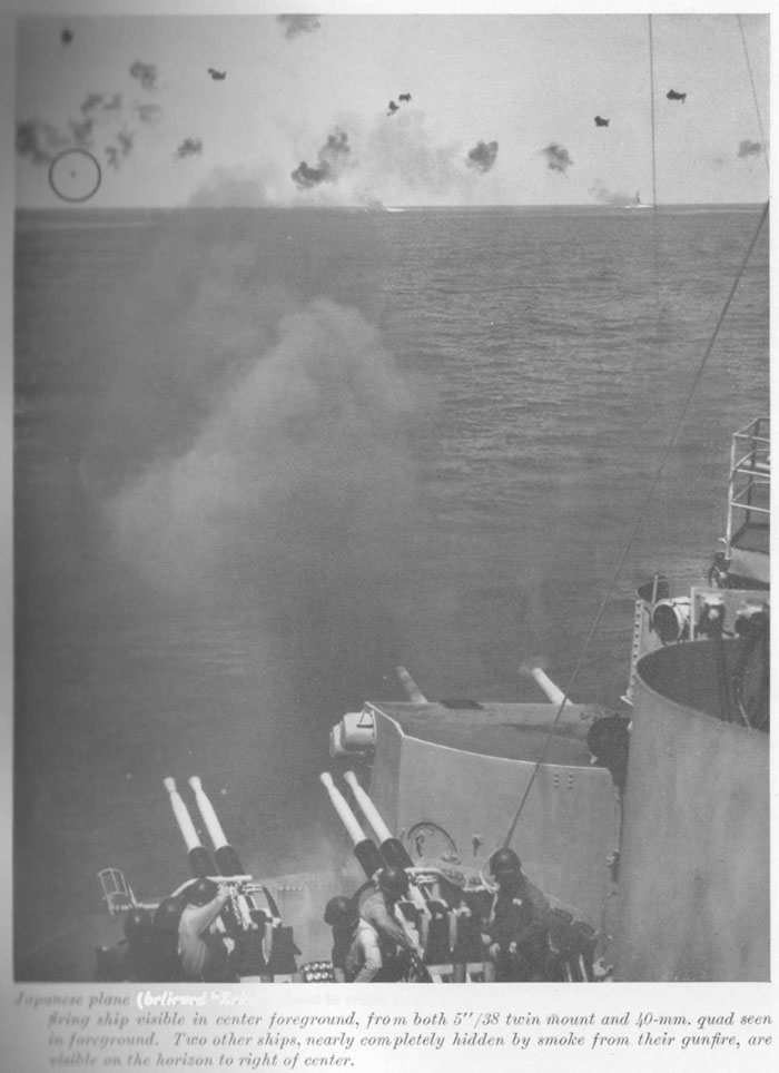 Japanese plane (believed "Zeke") about to crash in the sea as result of heavy AA fire. Smoke from firing ship visible in center foreground, from both 5"/38 twin mount and 40-mm. quad seen in foreground. Two other ships, nearly completely hidden by smoke from their gunfire, are visible on the horizon to right of center.
