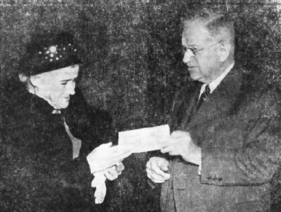 Image: Mrs. Etta S. Jones receives from Secretary Ickes a check for $6887.54, covering her salary for the years she spent as a prisoner in Japan. She was captured on Attu. 