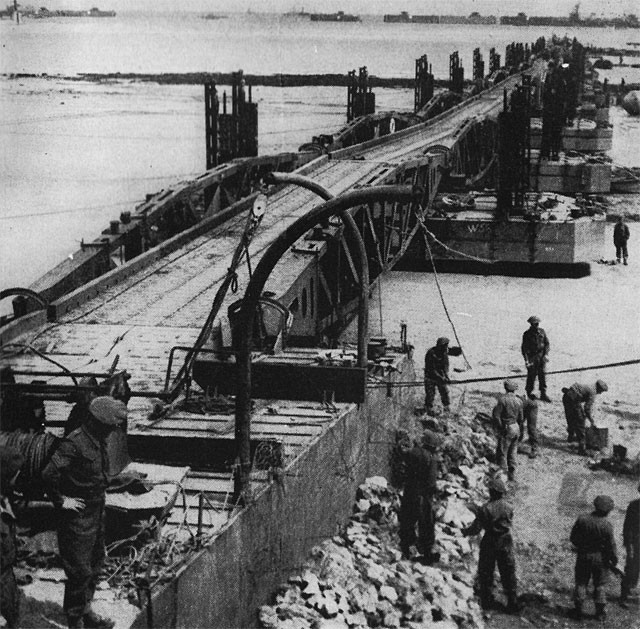Here are seen men of the Royal Engineers putting the finishing touches to the ramp on the Normandy end of the floating roadway. The job of assembling the harbor for U.S. supplies was done by the American Seabees.
