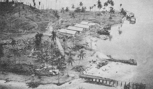 Image of 'Tanambogo after bombardment. Farther dock was scene of oil fire.'