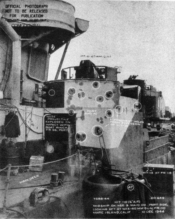Hit #10. Fragment damage caused by 6-inch projectile which detonated on striking the boat winch at frame 96, port side.