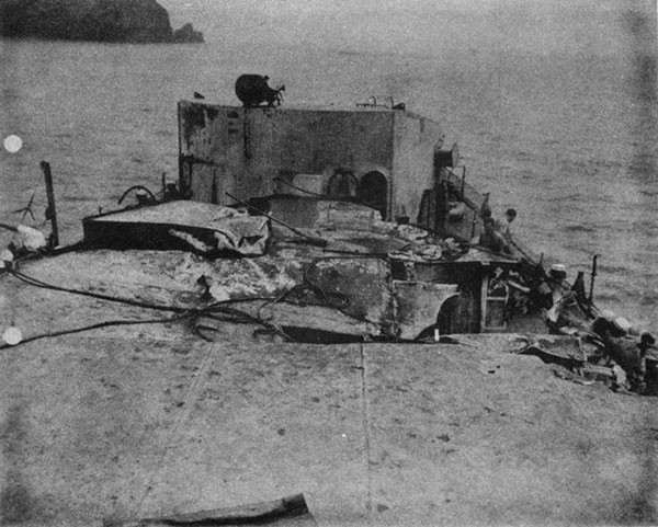 STORMES (DD780). After superstructure and No. 3 mount before temporary repairs. After torpedo mount has been jettisoned from foundation in foreground. The large hole is due to plane impact and to the blast of the air flask. A smaller hole further aft due to passage of bomb is not visible.