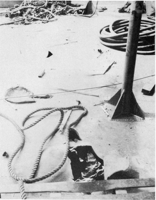 Photo 23: Fragment damage to shelter deck directly above hit, looking from port to starboard. Stanchions were bent by bulged deck plating. (U.S.S. ALHENA).