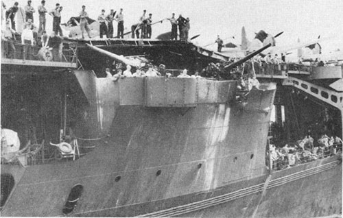 Photo E-12: Second hit. Group III gun gallery showing bulge in flight deck above guns caused by bomb explosion and ammunition blast.