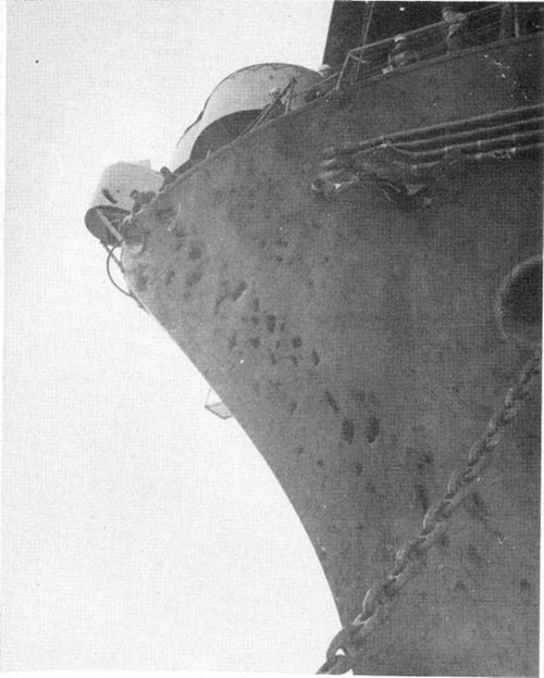Photo F-3: First hit. Bomb exit hole in way of degaussing cables and fragment holes on port bow.