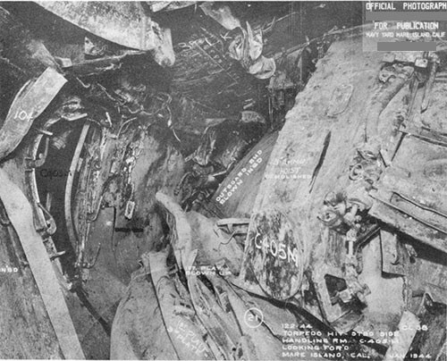 Photo 26: 5 inch handling room C-405-M looking forward. The 5-inch projectiles in this space were thrown about violently. Several fuses were almost destroyed by impact but only one showed evidence of detonating. No main charges detonated. See photo 12.